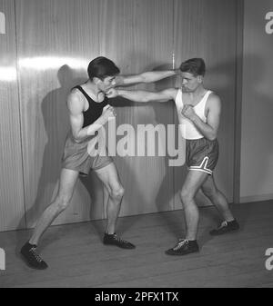 Due giovani boxer che si affrontano, vestiti per la boxe ma privi di guanti di boxe. Entrambi i punzoni terra, una sinistra diritta e una destra diritta grazie a entrambi che non riescono a mantenere la loro guardia in su. Svezia nel 1945. Kristoffersson rif L1-3 Foto Stock