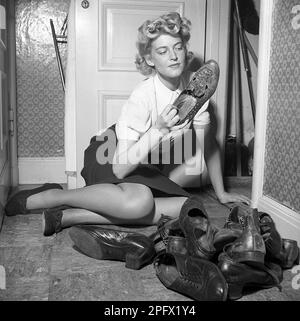 Scarpe negli anni '1940s. Una giovane donna con le scarpe davanti a lei, preso dall'armadio - le scarpe sono state usate per un po 'di tempo e ha bisogno di un lucidare. Svezia 1943 Kristoffersson Ref D57-2 Foto Stock