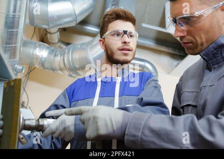 tecnici di fabbrica che utilizzano la piegatrice idraulica per tubi Foto Stock