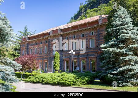 Vecchio stabilimento di imbottigliamento Borzhomi nel Parco Centrale di Borjomi, vecchio edificio in mattoni rossi con vegetazione lussureggiante e alberi intorno. Foto Stock