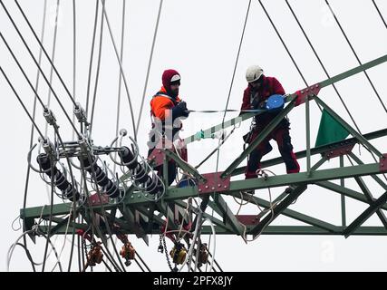 Birkenwerder, Germania. 02nd Mar, 2023. Due montatori di linee aeree di EQOS Energie preparano l'installazione della catena stando in piedi su una corda inferiore di traliccio di un traliccio ad alta tensione. Credit: Soeren Stache/dpa/Alamy Live News Foto Stock