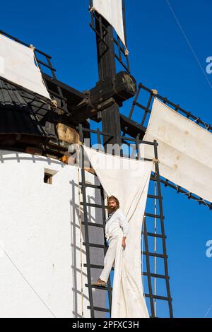 Campo de Criptana, Spagna - 22 giugno 2022: Mulino a vento con l'uomo che sale sulle pale per installare il tarpo per farlo funzionare Foto Stock