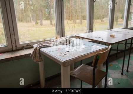 Tavoli vecchi e fatiscenti e tavolini da caffè in un edificio abbandonato. Foto Stock