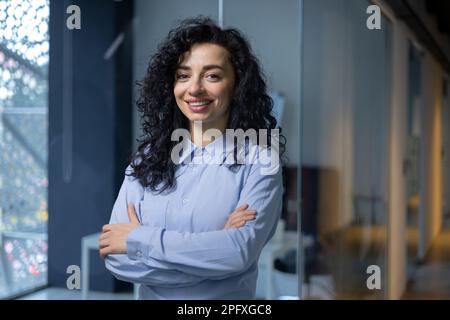 Ritratto di successo donna d'affari all'interno dell'ufficio sul posto di lavoro, donna ispanica soddisfatto con successo sorridente e guardando la macchina fotografica al lavoro con braccia incrociate boss in camicia sul corridoio aziendale. Foto Stock