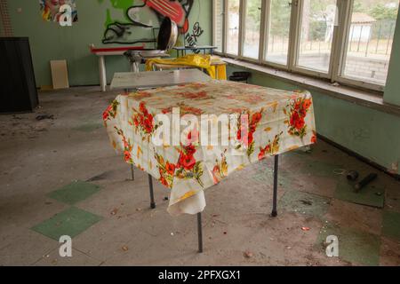 Tavoli vecchi e fatiscenti e tavolini da caffè in un edificio abbandonato. Foto Stock