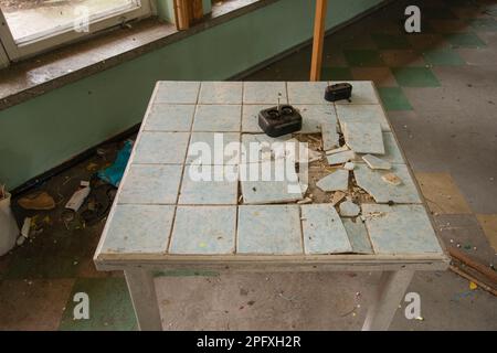 Tavoli vecchi e fatiscenti e tavolini da caffè in un edificio abbandonato. Foto Stock