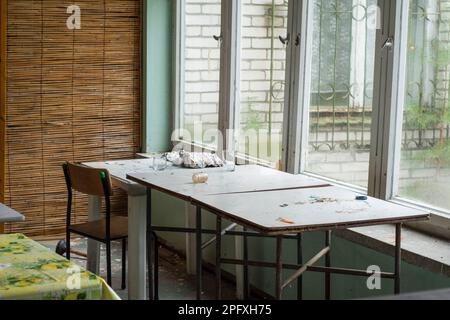 Tavoli vecchi e fatiscenti e tavolini da caffè in un edificio abbandonato. Foto Stock