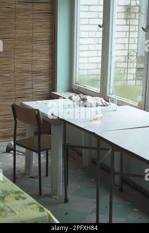 Tavoli vecchi e fatiscenti e tavolini da caffè in un edificio abbandonato. Foto Stock