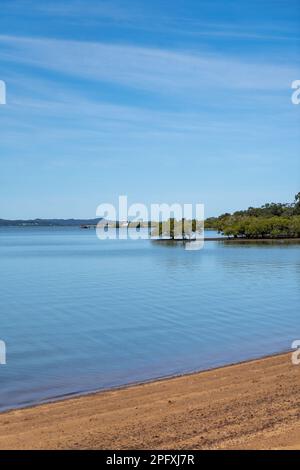 Vista dalla spiaggia di Redland Bay attraverso le belle e tranquille acque di Moreton Bay con il traghetto veicolare in lontananza e le isole all'orizzonte Foto Stock