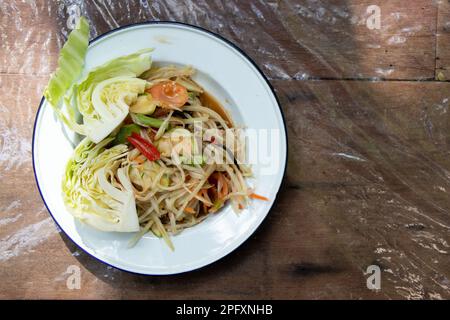 Insalata di papaya tailandese (Somtum) in piatto bianco su tavolo di legno Foto Stock