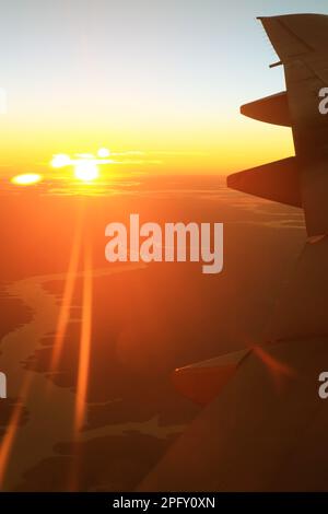 Sole luminoso che sorge con splendidi raggi di sole come si vede dalla finestra dell'aereo Foto Stock