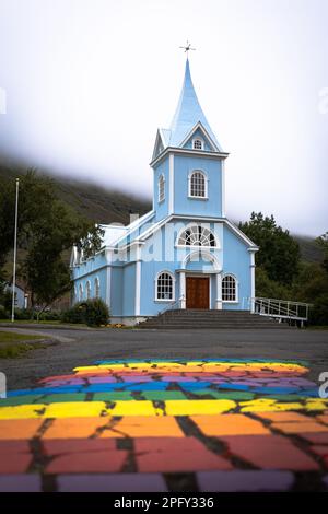 Le strisce arcobaleno sul marciapiede che conduce alla Chiesa Seydisfjordur in Islanda Foto Stock