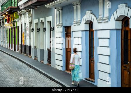 Donna che cammina per facciate colorate edificio, Old San Juan, Puerto Rico Foto Stock