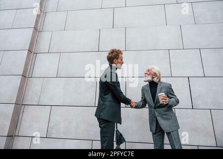 Avere un Meet. Giovane uomo con l'uomo anziano in abiti eleganti è all'aperto insieme. Concezione del business Foto Stock