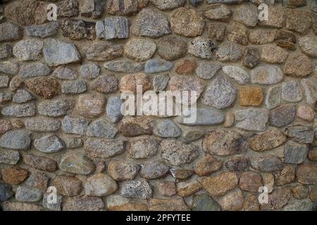Struttura di un muro di pietra. Parte di parete di roccia come sfondo o struttura. Forme, dimensioni e colori diversi combinati insieme. Foto Stock