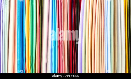 Mescolare tessuti colorati a strisce verticali, tessuti, panni sulla rastrelliera. Texture di tessuti multicolore primo piano. Foto Stock