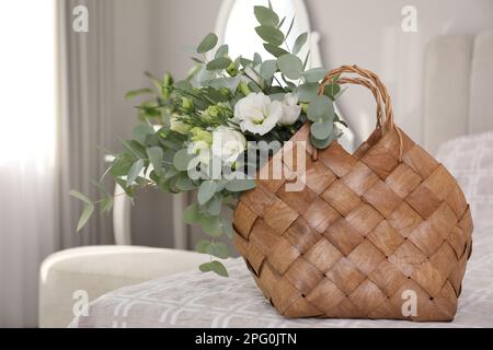 Elegante cesto di vimini con bouquet sul letto interno Foto Stock