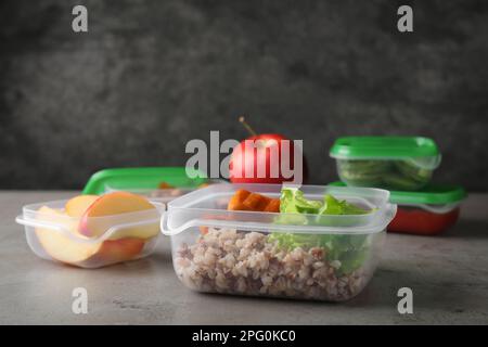 Set di contenitori in plastica con alimenti freschi su tavolo grigio chiaro Foto Stock