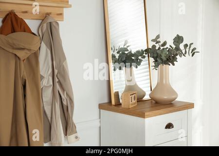 Un ingresso con un appendiabiti e una cassettiera in un appartamento.  Scarpe su scaffali e giacche su appendiabiti nel corridoio vicino alla  porta anteriore wi Foto stock - Alamy