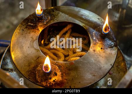 Lampada illuminata con stoppino in olio all'interno della lampada, monastero buddista, Thailandia. Foto Stock