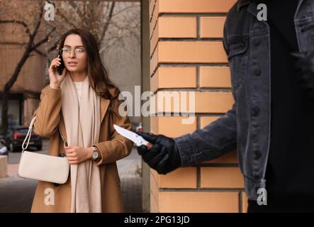 Criminale con coltello nascosto dietro il muro e in attesa di vittima vicino vicolo Foto Stock