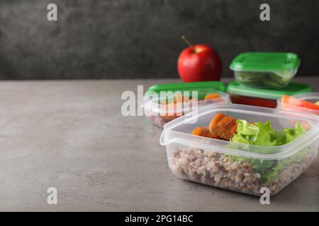 Set di contenitori in plastica con alimenti freschi su tavolo grigio chiaro, spazio per testo Foto Stock