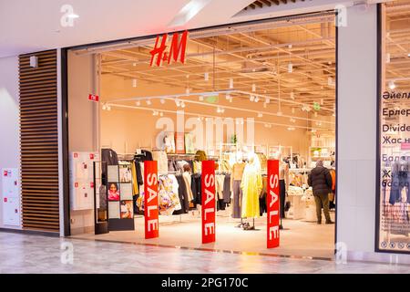 Negozio HM. Hennes e Mauritz, hm, H e M. segno di vendita sul sensore anti-furto cancello all'ingresso del negozio di abbigliamento, grandi pannelli rossi. Vendita rosso brillante b Foto Stock