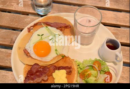 Deliziosa colazione con frittelle dolci nel caffè illuminato dal sole. Foto Stock