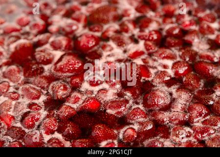 Marmellata di fragole che simmering leggermente, dettaglio primo piano, vista dall'alto. Bella marmellata di fragole in cottura. Marmellata di fragole fatta in casa bollente. Preparazione di una marmellata di fragole fatta in casa. Far bollire la frutta in una padella Foto Stock