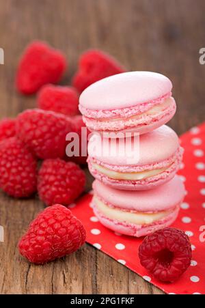 Biscotti rosa al macaron di lamponi su tavole di legno scuro Foto Stock