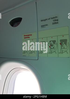 istruzioni su come aprire la porta di emergenza nella fila delle uscite di emergenza su un aeromobile airbus a bordo a metà volo Foto Stock