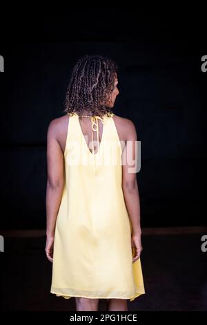 Vista posteriore della donna nera vestita di giallo Foto Stock
