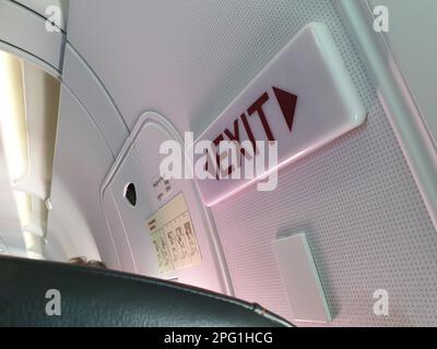 luce di uscita e porte nella fila delle uscite di emergenza posti a sedere su un aeromobile airbus a bordo a metà volo Foto Stock