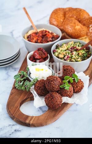 Scheda shabbat salumi: pane challah, falafel, insalata di quinoa, hummus. Concetto di cibo vegano israeliano. Foto Stock