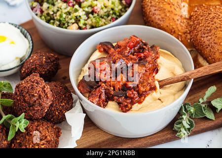 Hummus con recipiente di melanzane su un pletter partito. Concetto di cibo israeliano. Foto Stock