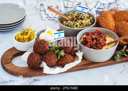 Tavolo tradizionale Shabbat: pane challah, falafel, insalata di quinoa, hummus su un asse di legno. Concetto di cibo israeliano. Foto Stock