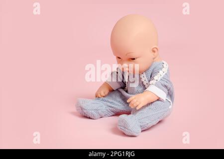 Bambola con testa calva su sfondo rosa studio. Giocattolo per bambini senza capelli, spazio copia Foto Stock