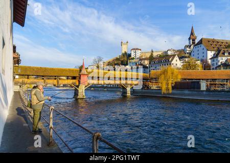 Lucerna, Svizzera - 22 febbraio 2023: Vista sul Ponte Spreuer, un pescatore e il fiume Reuss, con altri edifici, a Lucerna (Lucerna), Swit Foto Stock