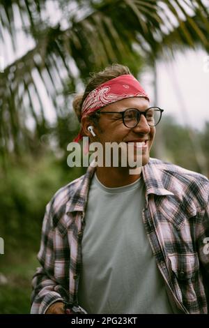 Giovane uomo hippie alla moda in bandana rossa e bicchieri. Vita di isola Foto Stock