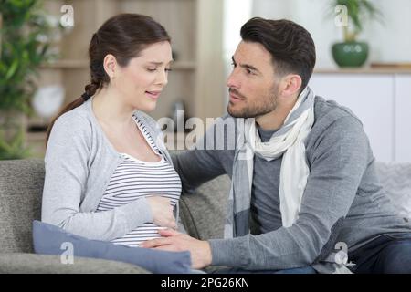 l'uomo e la donna incinta in soggiorno che guarda preoccupato Foto Stock