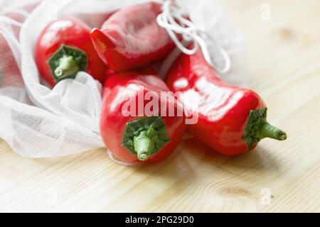 Paprika rossa in borsa riutilizzabile su un tavolo di legno. Il concetto di zero rifiuti e di uno stile di vita ecocompatibile. Niente plastica, primo piano Foto Stock