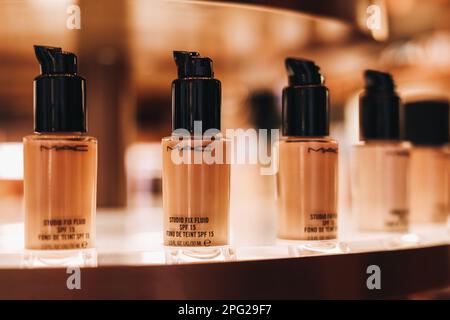 Tubi di vetro di Mac beige fondazione su uno stand in un negozio. Il concetto di cosmetici decorativi per il viso. Foto Stock