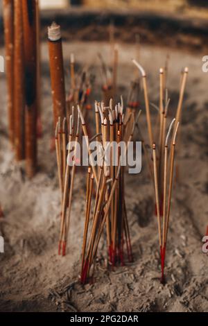 Bastoncini di incenso marrone che bruciano. Dettagli di spiritualità tradizionale per la meditazione e il relax. Verticale Foto Stock