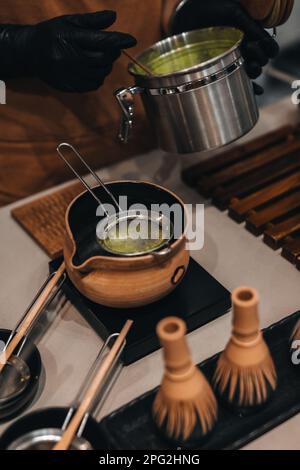 Processo di preparazione del tè verde Matcha. Vita morta con gli accessori biologici giapponesi Matcha tradizionali sul tavolo. Foto Stock