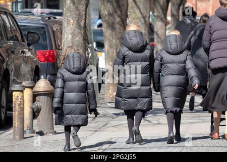 3 studenti ortodossi hassidici anonimi e non identificabili che tornano a casa dalla scuola indossando cappotti invernali identici. A Brooklyn, New York. Foto Stock