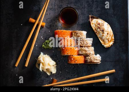Sushi, panini e cozze al forno su sfondo scuro con vista dall'alto delle bacchette cinesi. Pesce sano con salsa e zenzero. Cibo cinese. Foto Stock