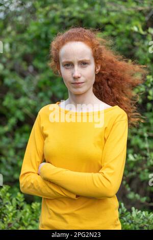 Primo piano ritratto di una ragazza donna capelli rossi con lenticchi guardando la macchina fotografica indossando t shirt gialla Foto Stock