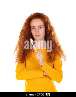 Ragazza sorridente attraente che guarda felicemente in macchina fotografica spazzolando i denti sopra sfondo bianco Foto Stock