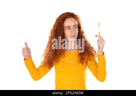 Ragazza sorridente attraente che guarda felicemente in macchina fotografica spazzolando i denti sopra sfondo bianco Foto Stock