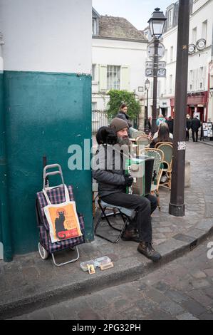 Busker francese parigino con fisarmonica con un gatto nero sulla spalla e borsa 'chat noir', suona nella piazza degli artisti Place du Tertre a Montmartre Foto Stock